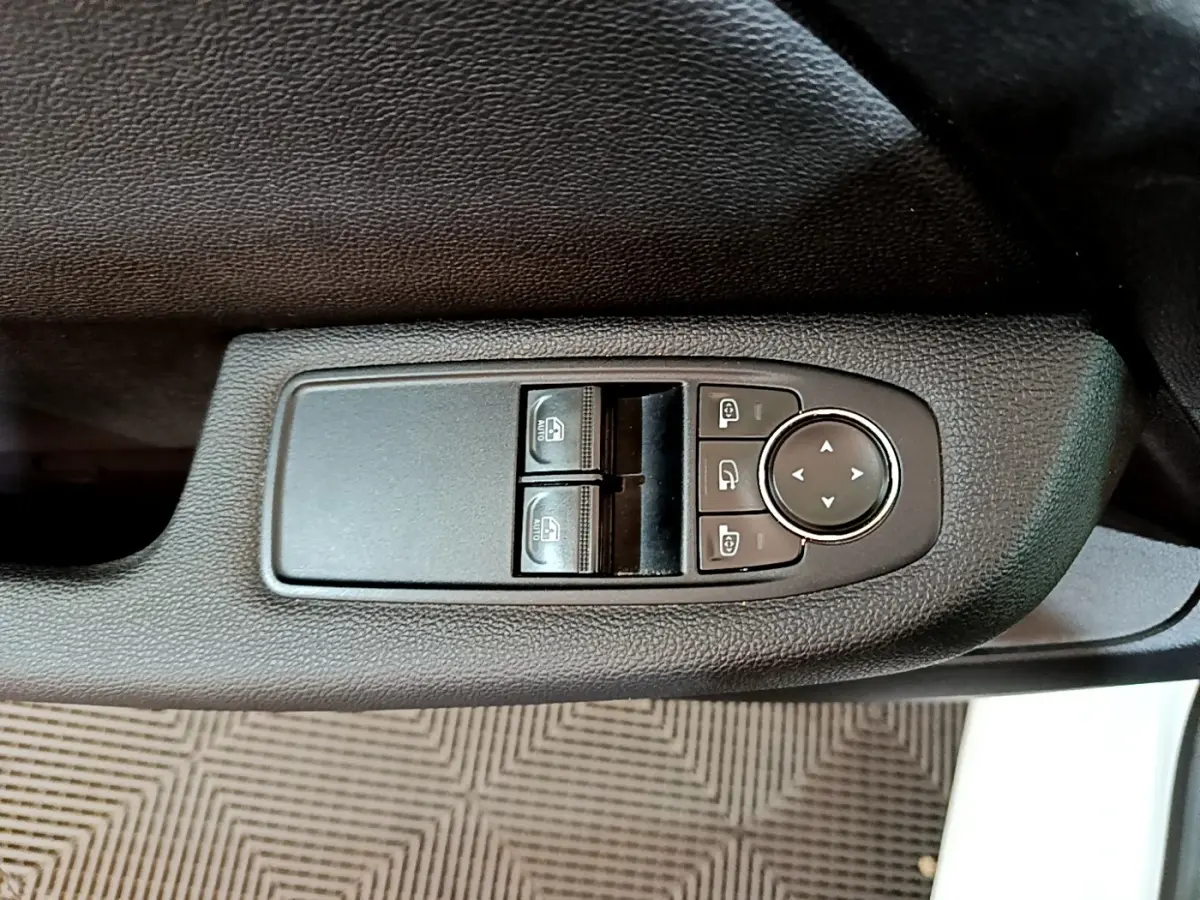 Gros plan sur les commandes de lève-vitres et réglage des rétroviseurs côté conducteur d'une Renault Clio blanche 2019.