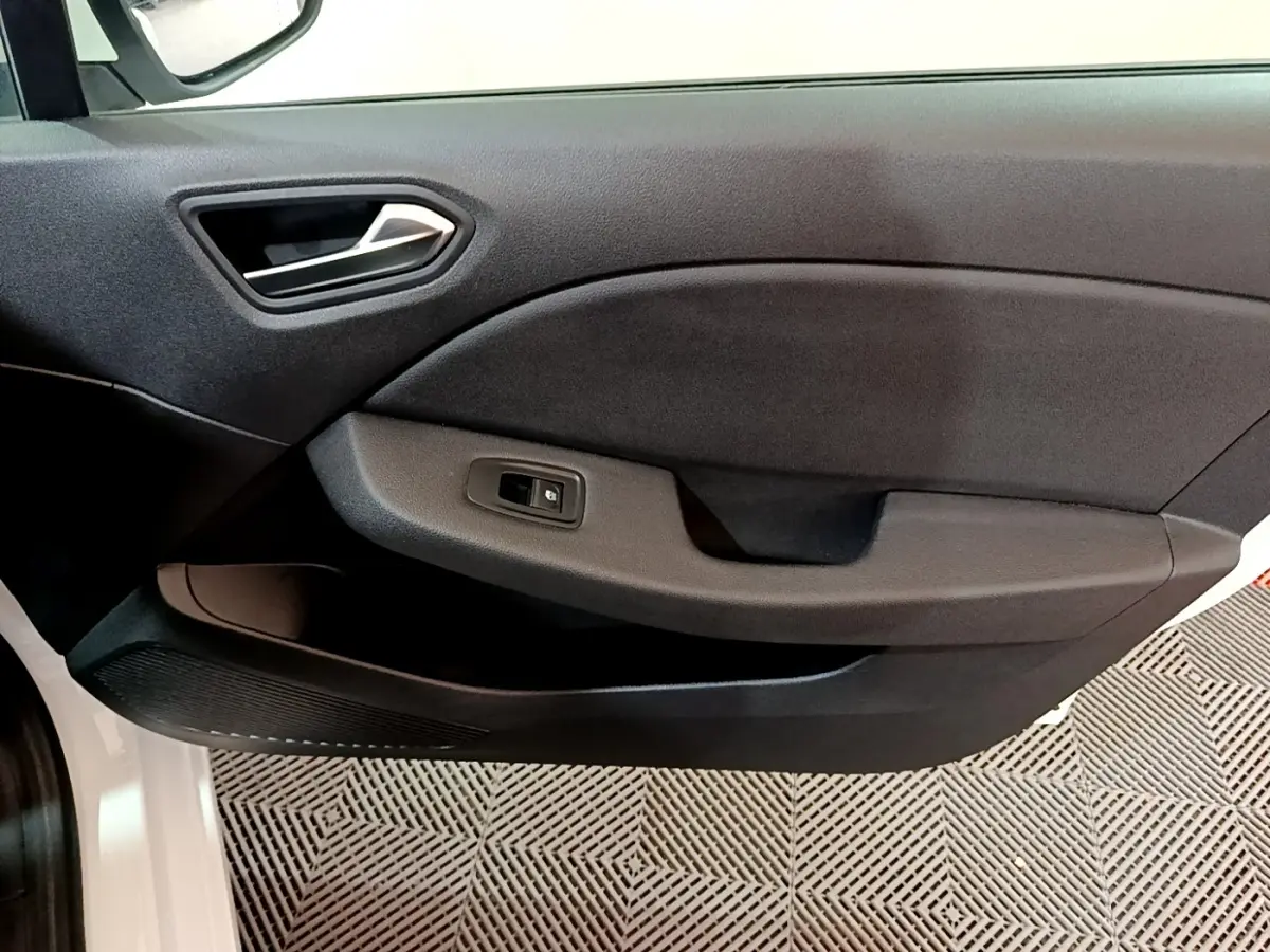 Gros plan sur la porte côté gauche intérieure noire de la Renault Clio Business blanche, avec poignée et bouton de vitre électrique visible.