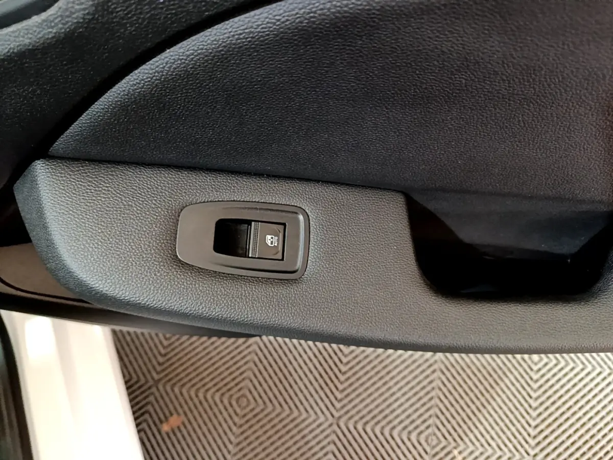 Gros plan sur le bouton de verrouillage centralisé dans la portière côté conducteur d'une Renault Clio blanche 2019.