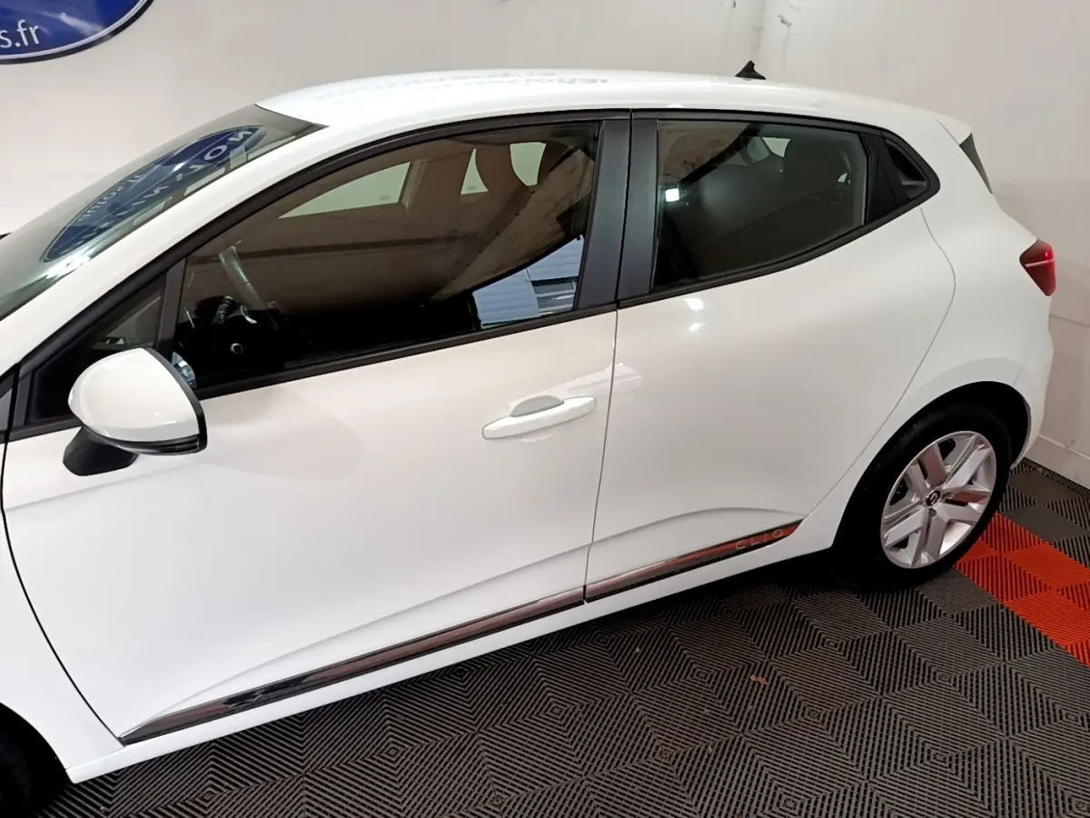 Profil côté gauche de la Renault Clio Business TCe 100 blanche, avec jantes alliage et poignées de porte assorties.