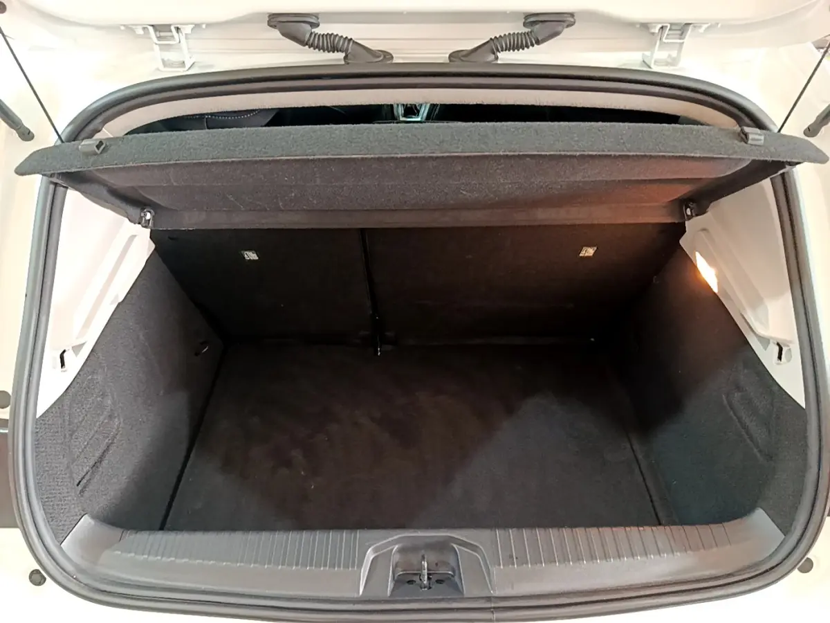 Coffre ouvert vu de l'arrière d'une Renault Clio Business TCe 100 blanche, montrant l'espace de chargement vide et la tablette de séparation.