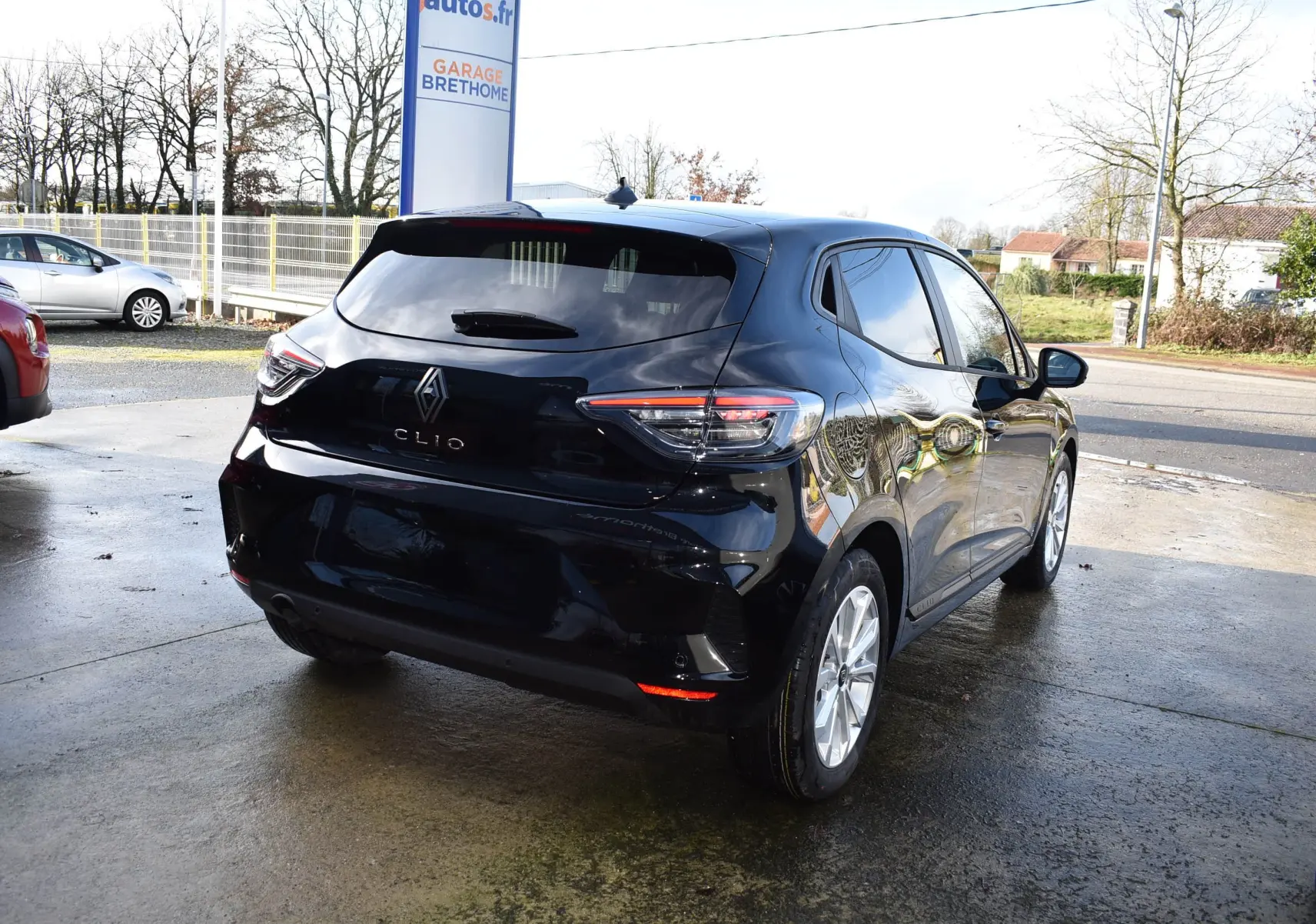 Vue 3/4 arrière droite d'une Renault Clio V noire 5 portes, avec feux arrière LED et jantes argentées, stationnée en extérieur.