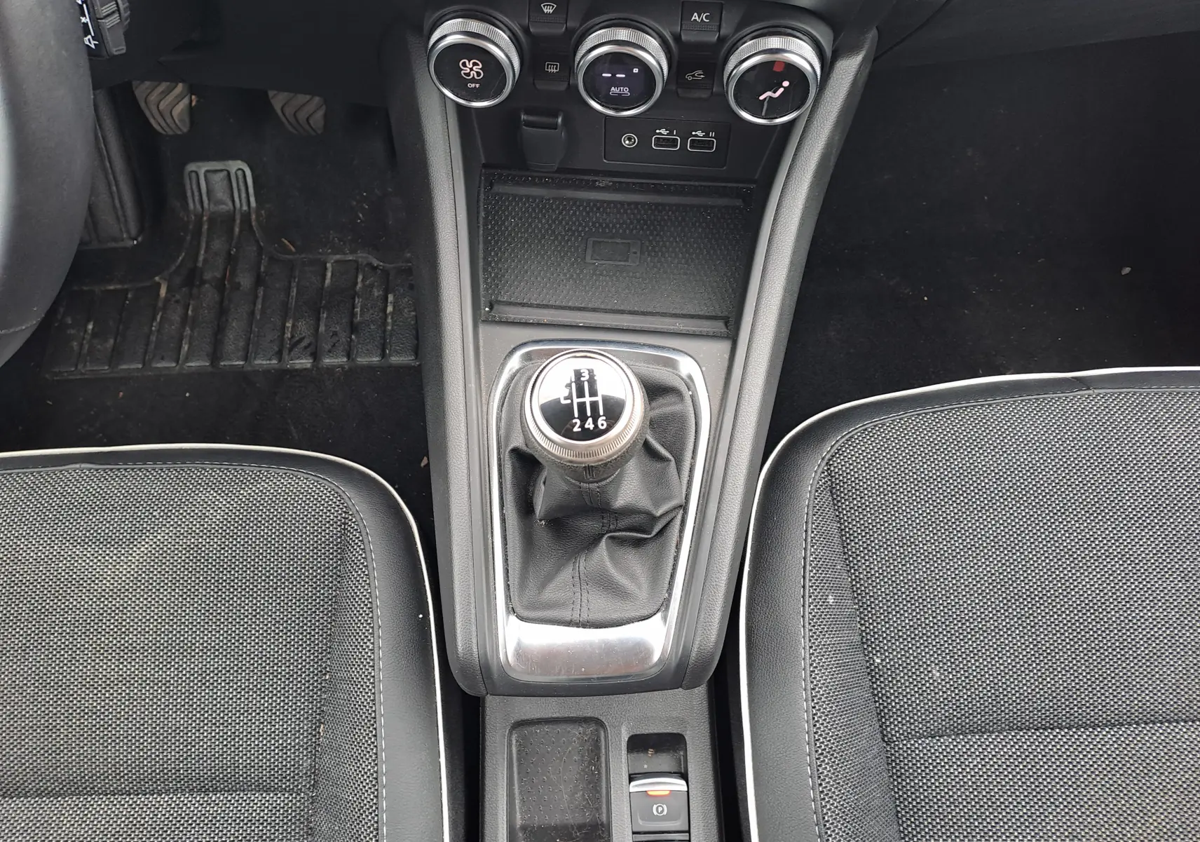 Vue plongeante sur la console centrale du Renault Captur 2024, mettant en valeur la boîte manuelle et les sièges noirs.