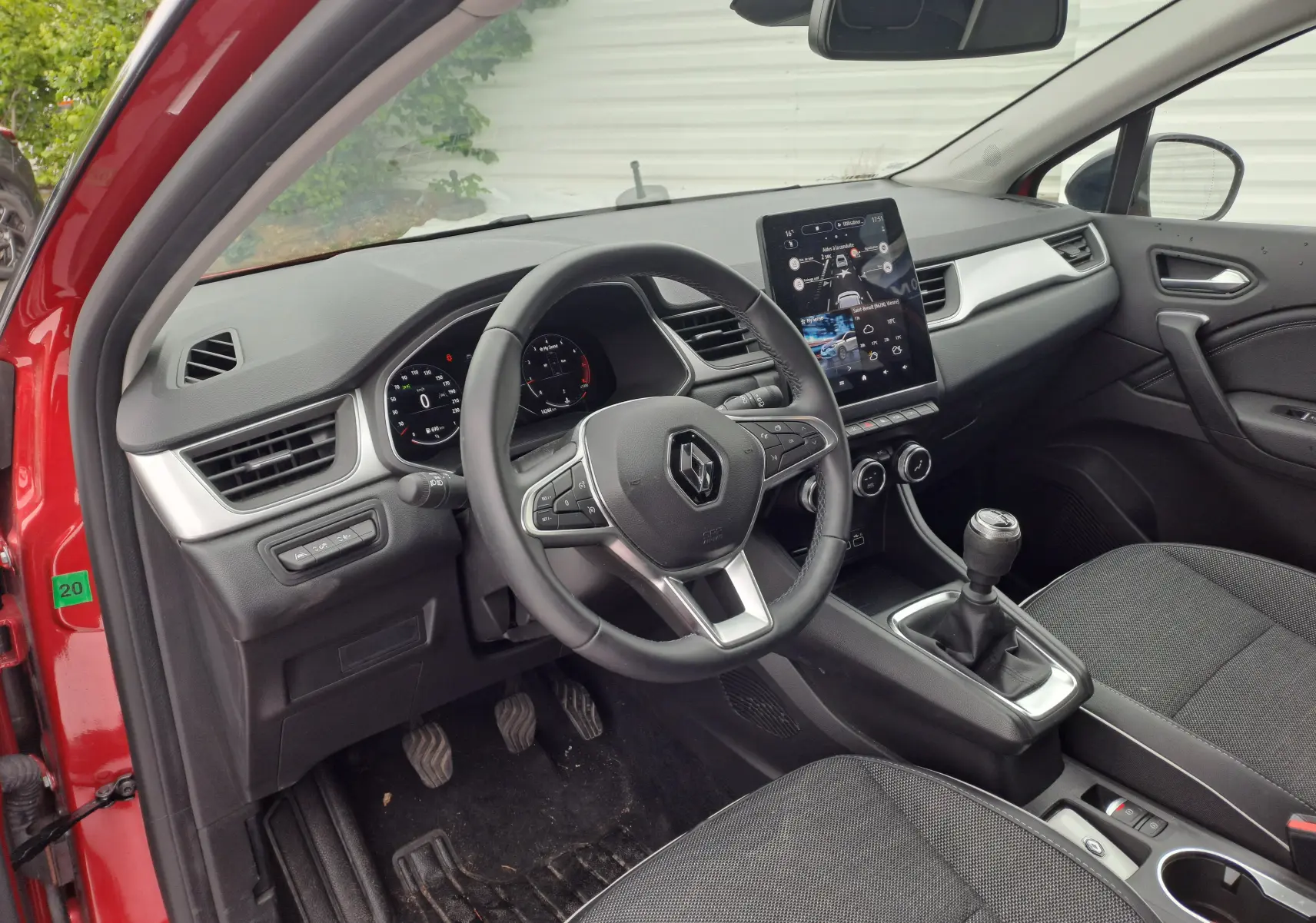 Intérieur du Renault Captur TCE 90CH TECHNO 2024 rouge flamme, vue côté conducteur avec tableau de bord et écran tactile vertical.