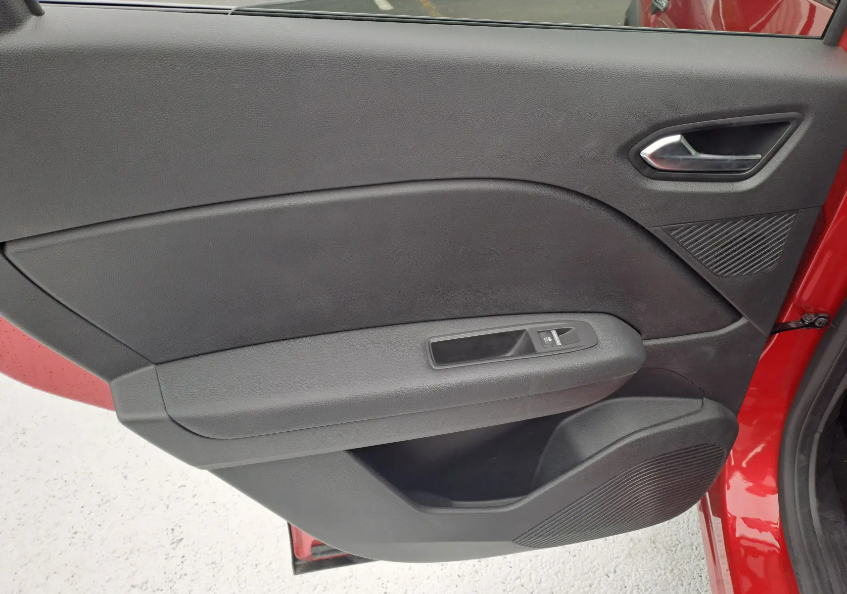 Vue rapprochée de la porte arrière droite noire avec poignée et commande de vitre du Renault Captur rouge flamme 2024.