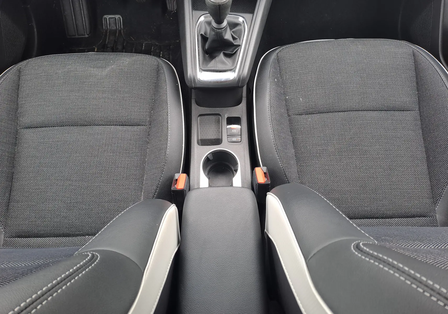 Vue plongeante sur les sièges avant noirs et la console centrale avec levier de vitesse manuelle du Renault Captur 2024.
