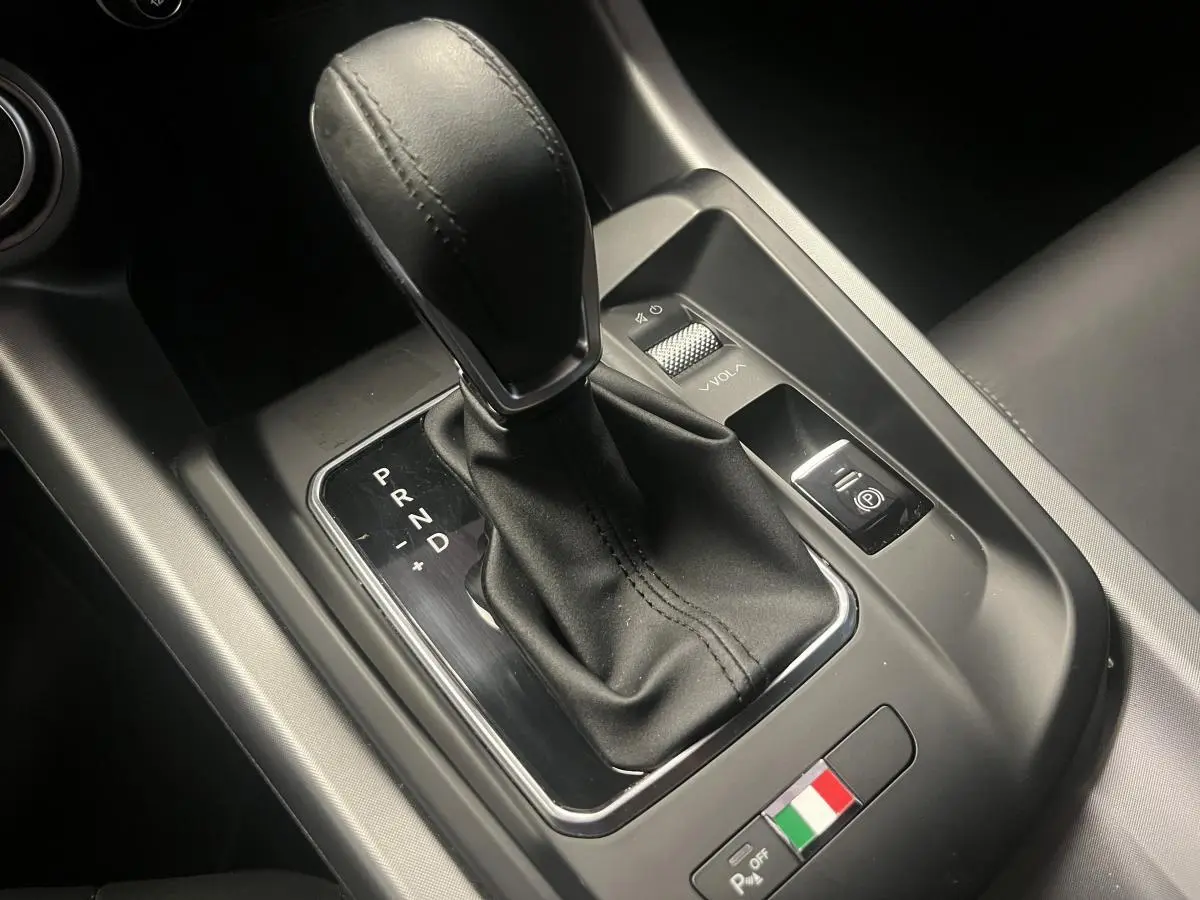 Le levier de vitesse automatique cuir noir de l'Alfa Romeo Tonale 2024 avec badge tricolore italien sur console centrale.
