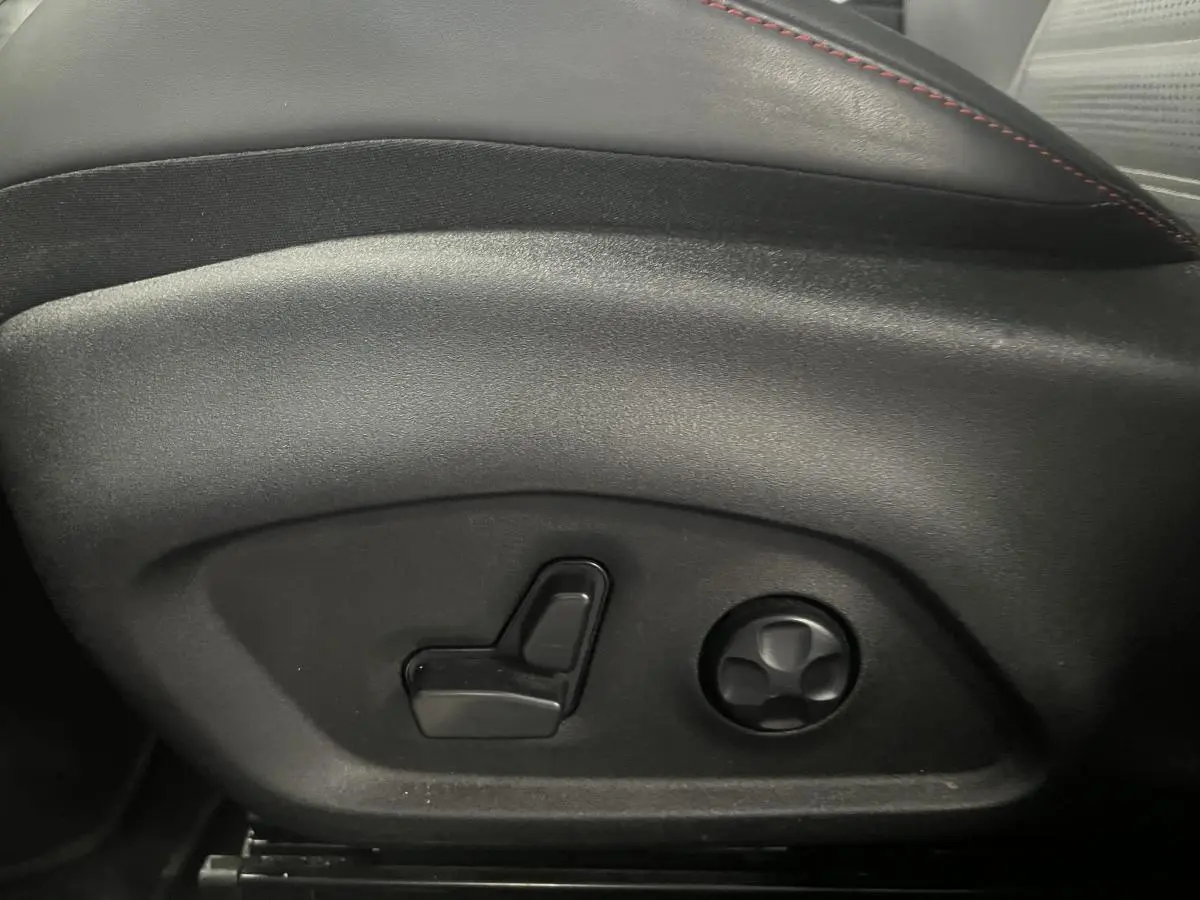 Gros plan sur les commandes électriques du siège conducteur en cuir noir avec surpiqûres rouges de l'Alfa Romeo Tonale 2024.