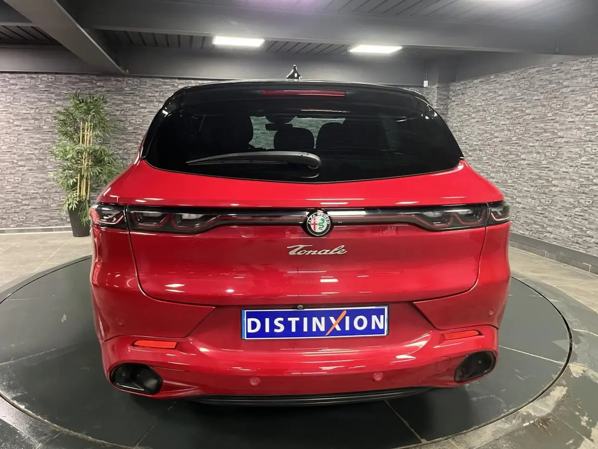 Vue arrière d'une Alfa Romeo Tonale rouge avec toit noir et feux arrière full LED dans un showroom.