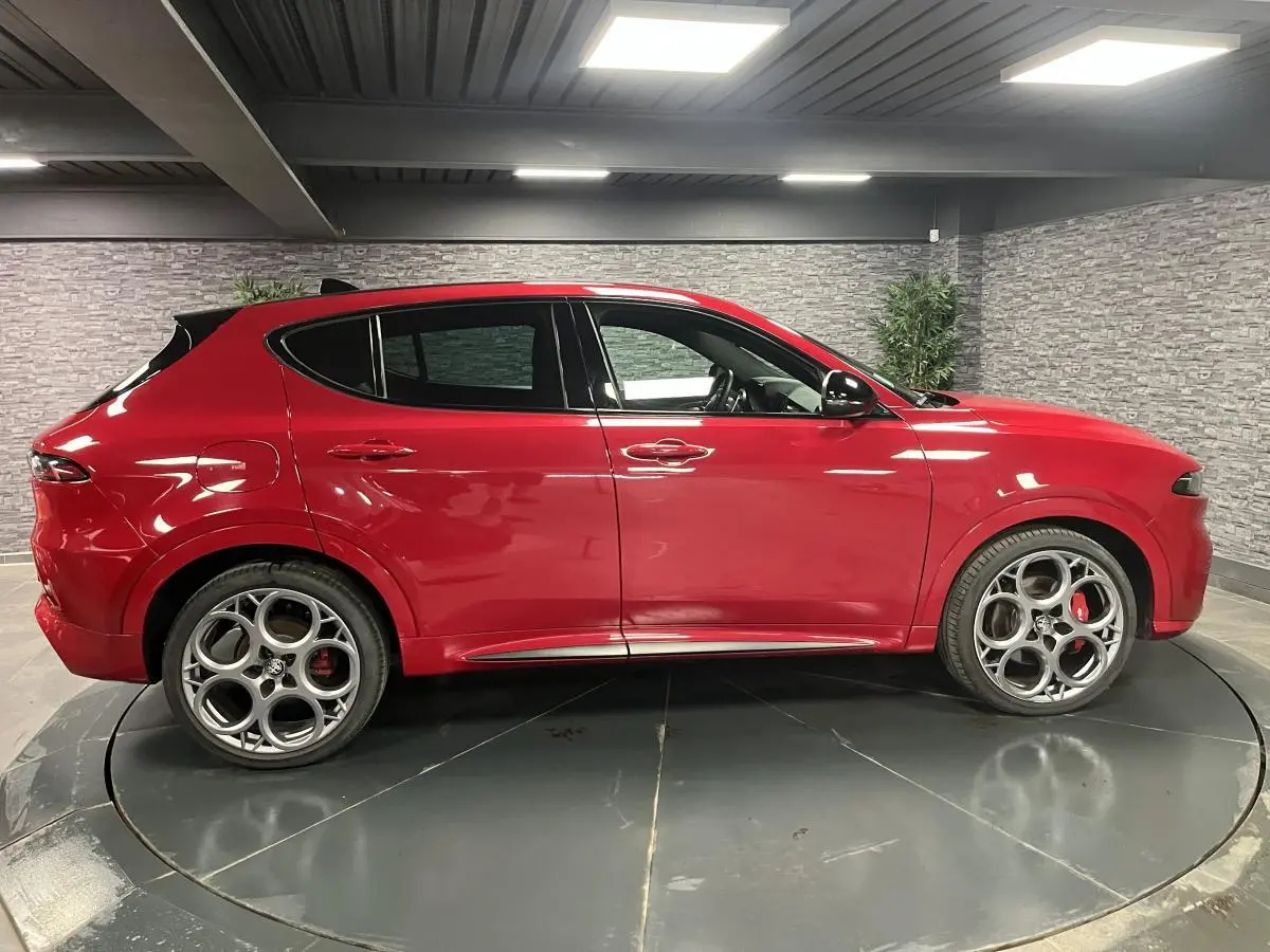Profil côté gauche de l'Alfa Romeo Tonale rouge avec jantes alliage 20 pouces et rétroviseurs noirs brillants.