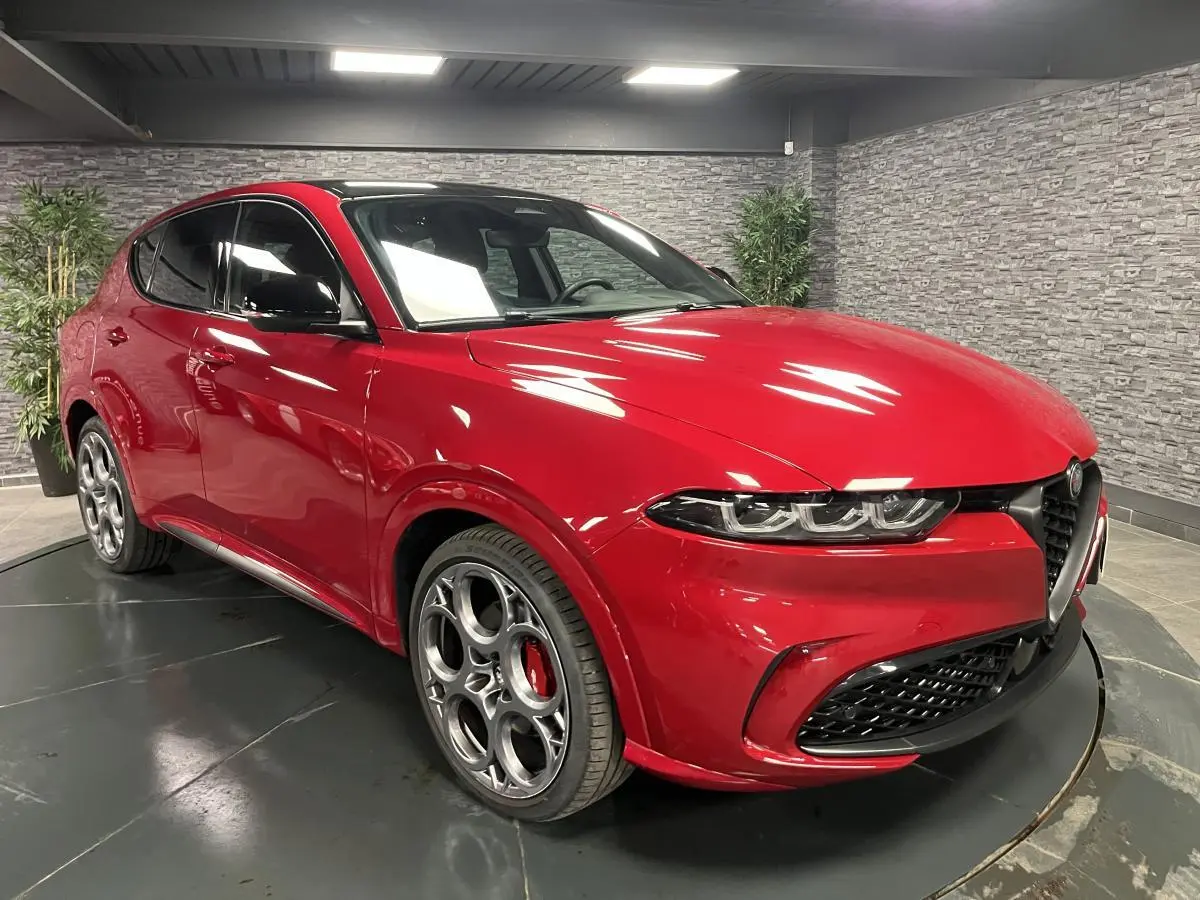 Alfa Romeo Tonale rouge vue 3/4 avant droit avec jantes 20 pouces et toit noir en intérieur showroom.