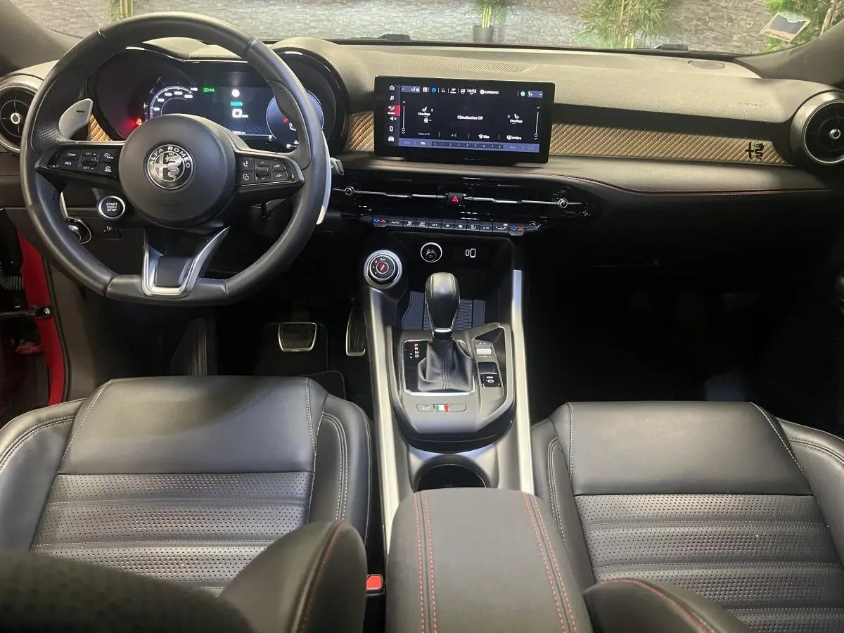 Intérieur de l'Alfa Romeo Tonale 2024 vu de face, volant sport cuir noir, tableau de bord digital et console centrale moderne.