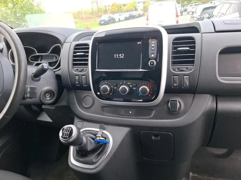 Vue intérieure du tableau de bord du Renault Trafic Fourgon blanc 2021, avec écran central, commandes de climatisation et levier de vitesse manuel.