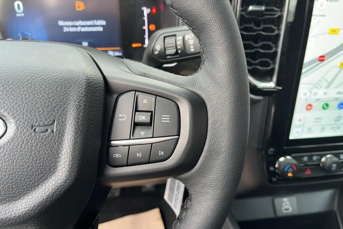 Gros plan sur le volant cuir multifonctions du Ford Ranger 2025 avec écran tactile et commandes au volant visibles.