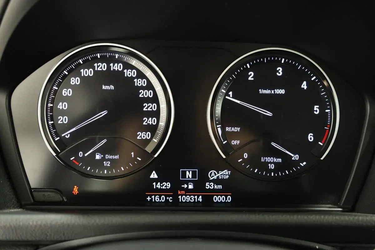 Gros plan sur le tableau de bord numérique de la BMW Série 2 Active Tourer 216d, affichant vitesse, régime et informations de conduite.