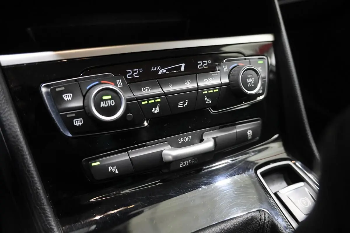 Vue rapprochée de la console centrale de la BMW Série 2 Active Tourer 216d, avec commandes de climatisation et modes de conduite.