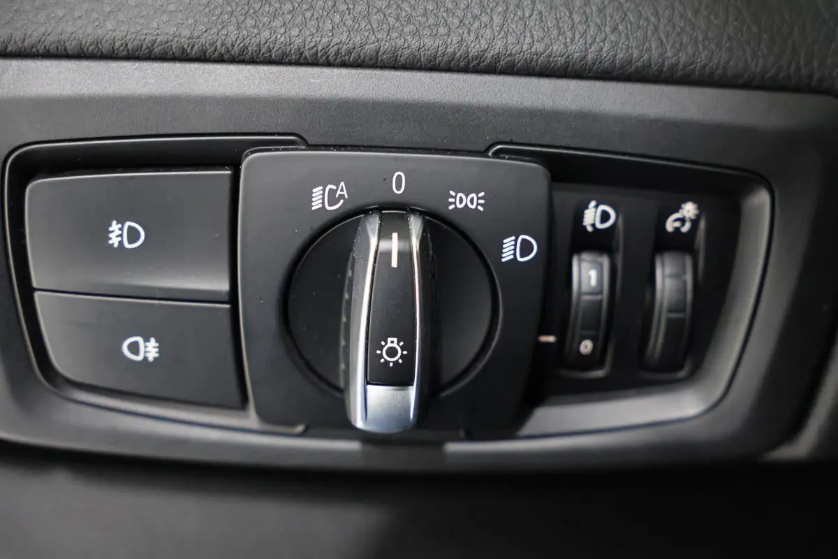 Gros plan sur la commande des phares et réglages lumineux intérieurs d'une BMW Série 2 Active Tourer blanche.