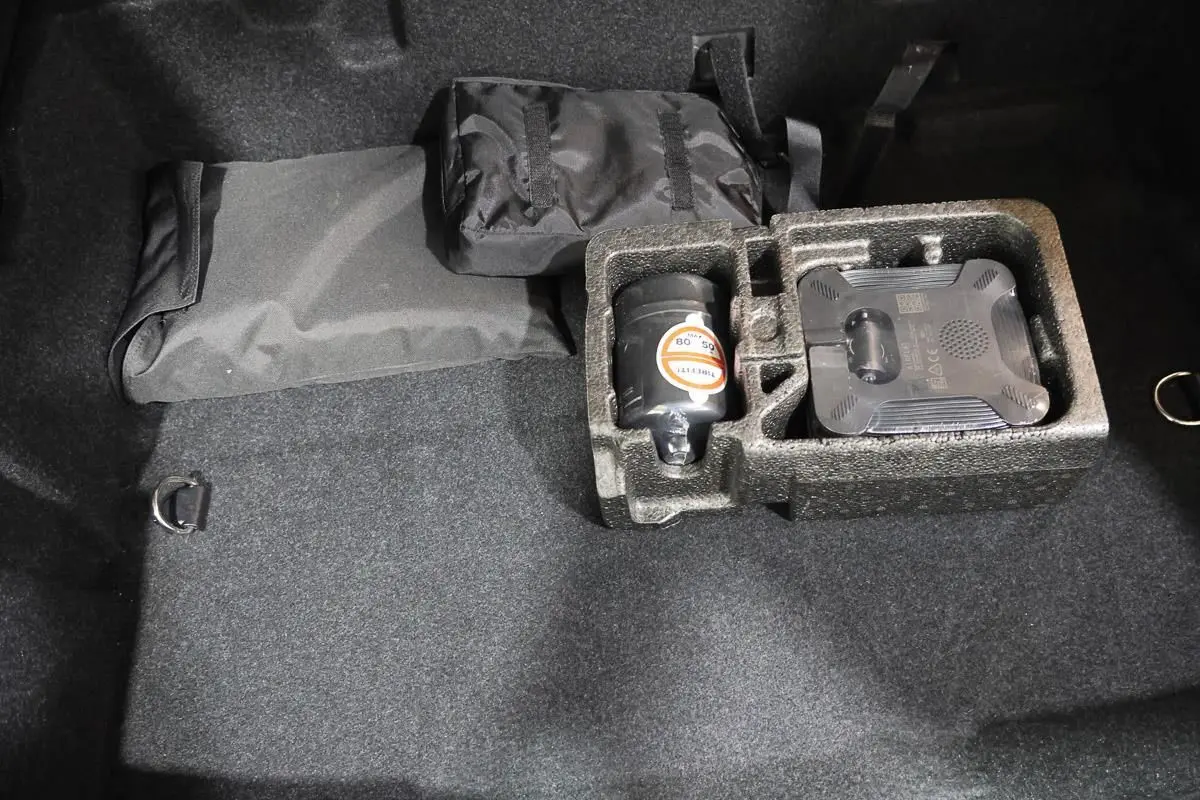 Vue intérieure du coffre noir de la BMW Série 2 Active Tourer 216d avec rangement en mousse et accessoires rangés.