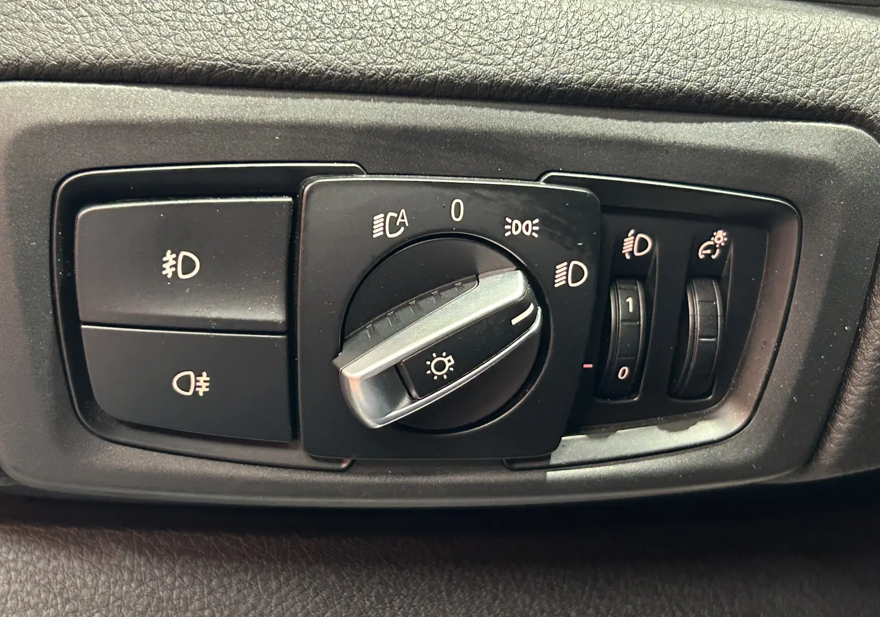 Gros plan sur la commande des phares et réglages d’éclairage intérieur d’une BMW Série 2 Active Tourer blanche.