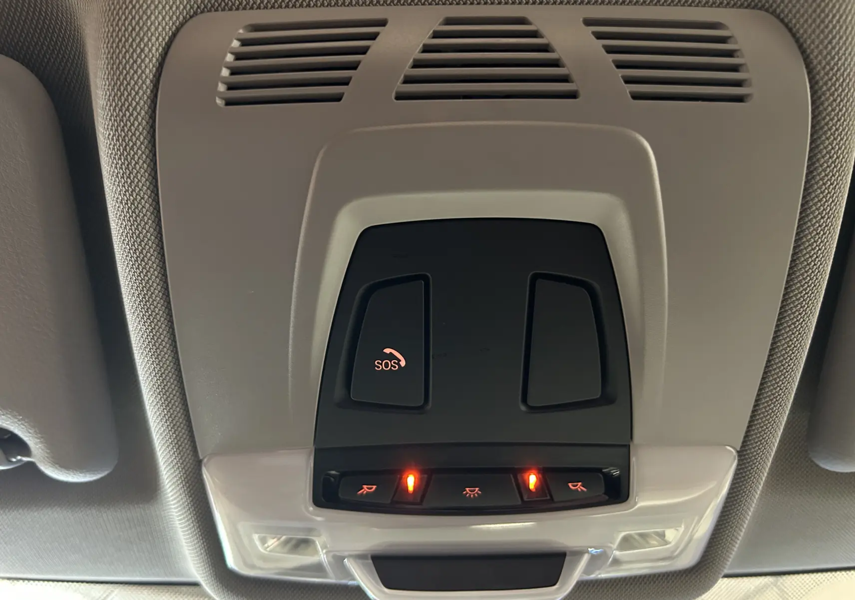 Vue en gros plan du plafonnier intérieur gris avec boutons SOS et éclairage allumé dans une BMW Série 2 Active Tourer 216d blanche.