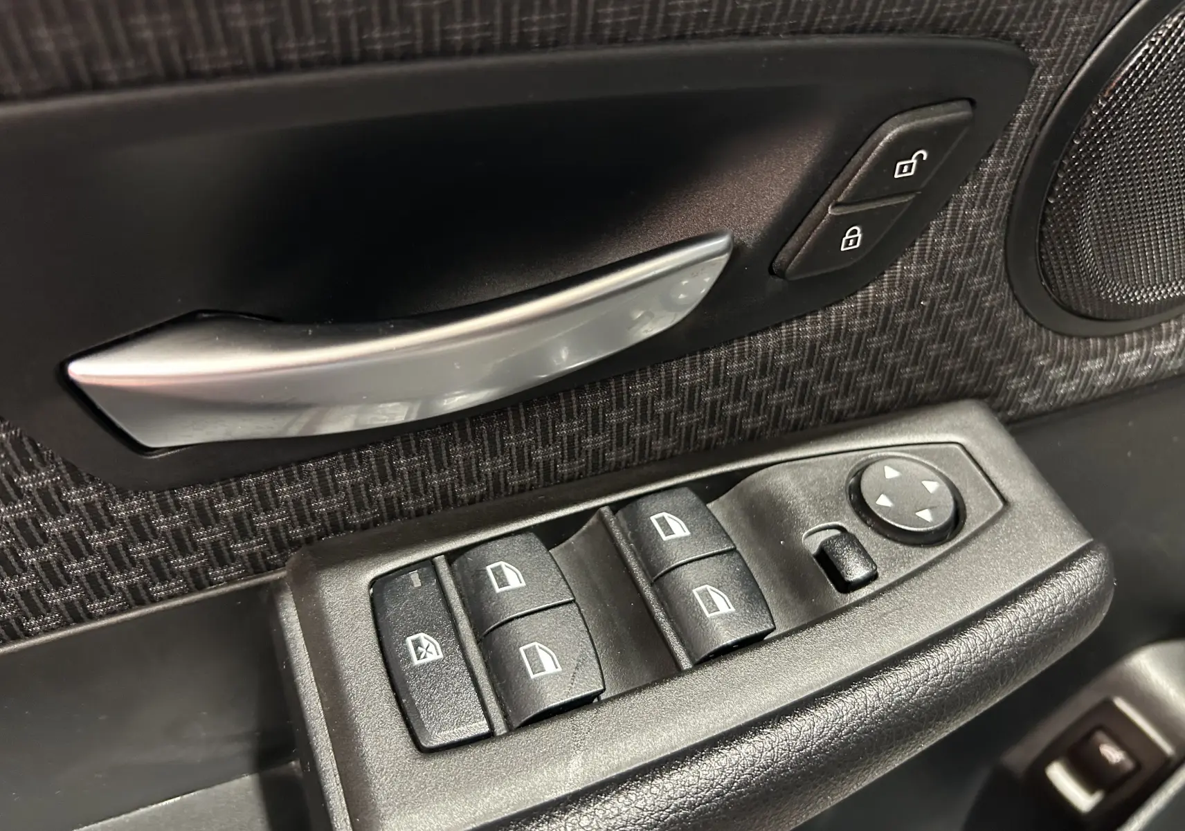 Gros plan sur la commande des vitres et la poignée intérieure côté conducteur d’une BMW Série 2 Active Tourer blanche.