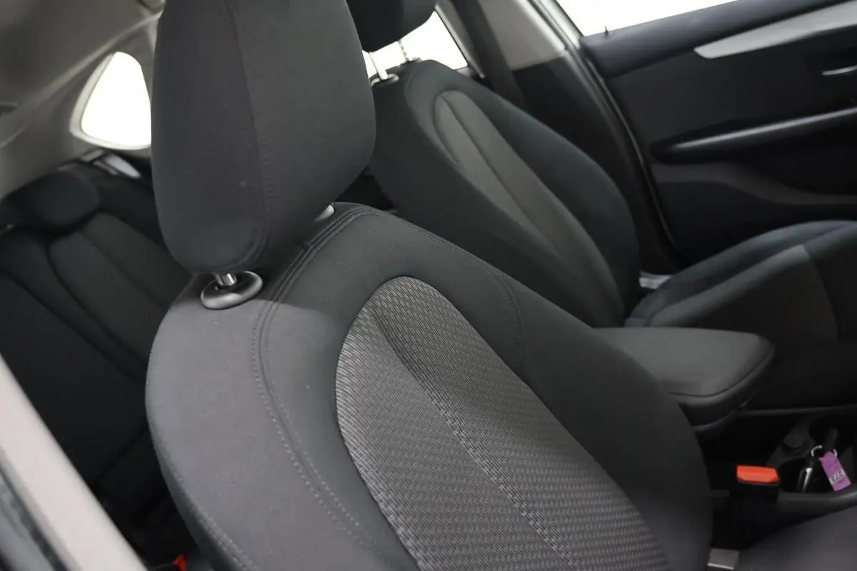 Gros plan sur les sièges avant en tissu gris foncé de la BMW Série 2 Active Tourer blanche, vue côté droit intérieur.