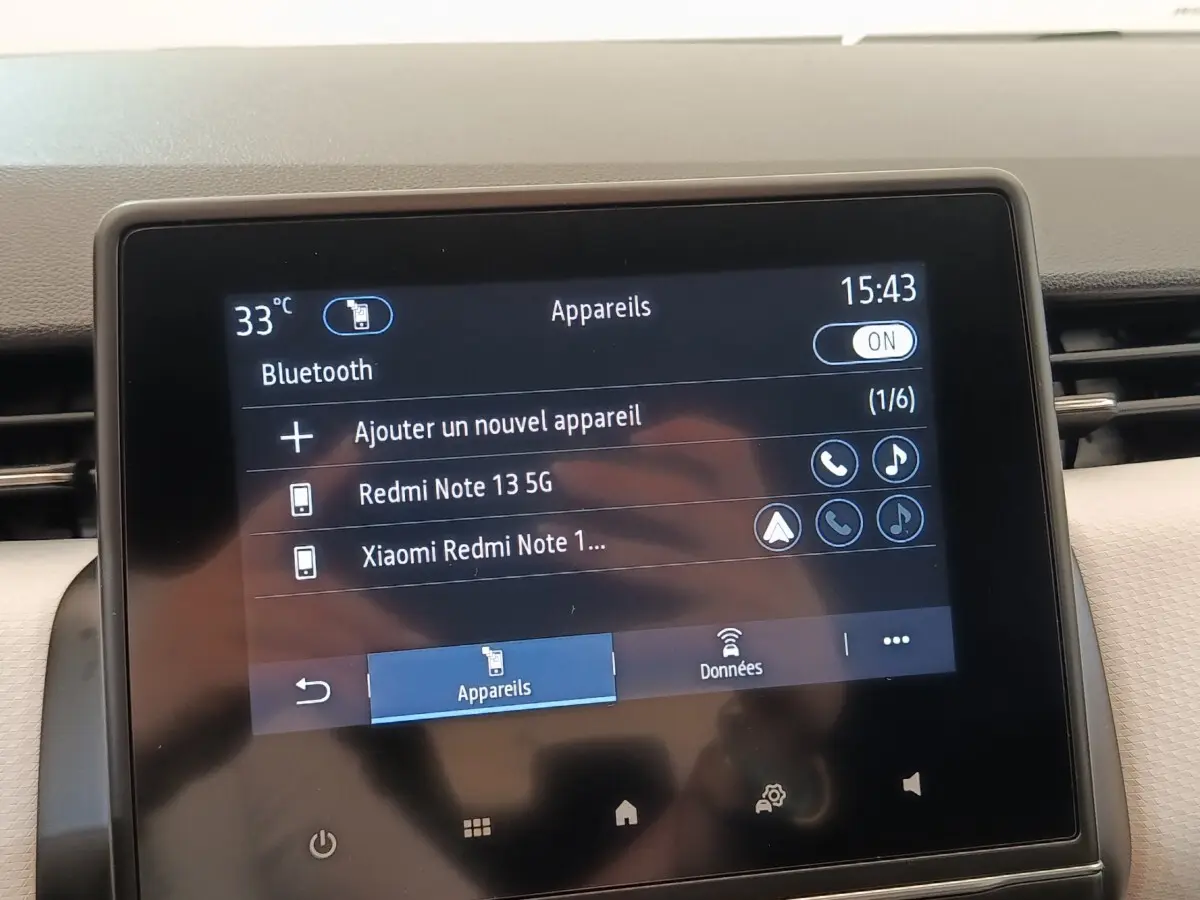 Écran tactile central de la Renault Clio blanc, affichant la connexion Bluetooth avec deux appareils listés.