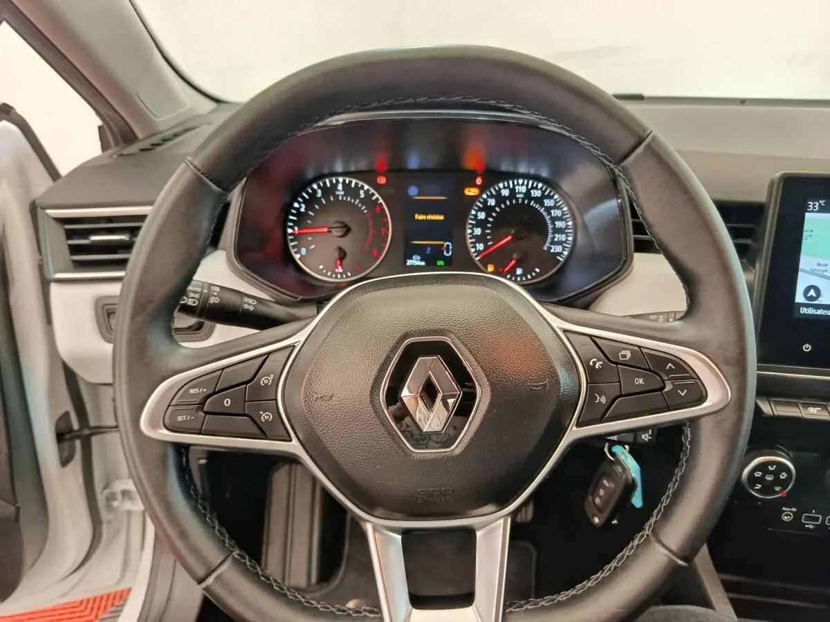 Vue intérieure centrée sur le volant cuir noir de la Renault Clio 2023 avec tableau de bord et écran tactile visible.