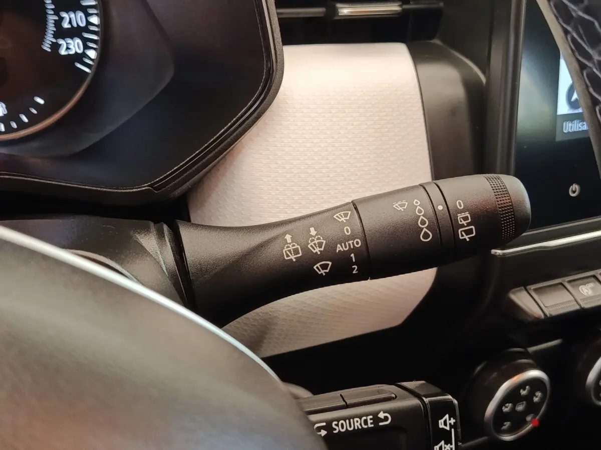 Gros plan sur la commande des essuie-glaces côté gauche du tableau de bord blanc de la Renault Clio Evolution TCe 100 GPL 2023.