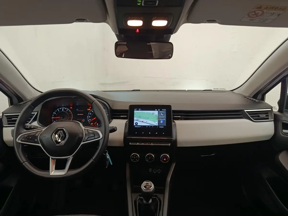 Vue intérieure frontale du tableau de bord de la Renault Clio blanc, avec écran tactile central et volant multifonctions.