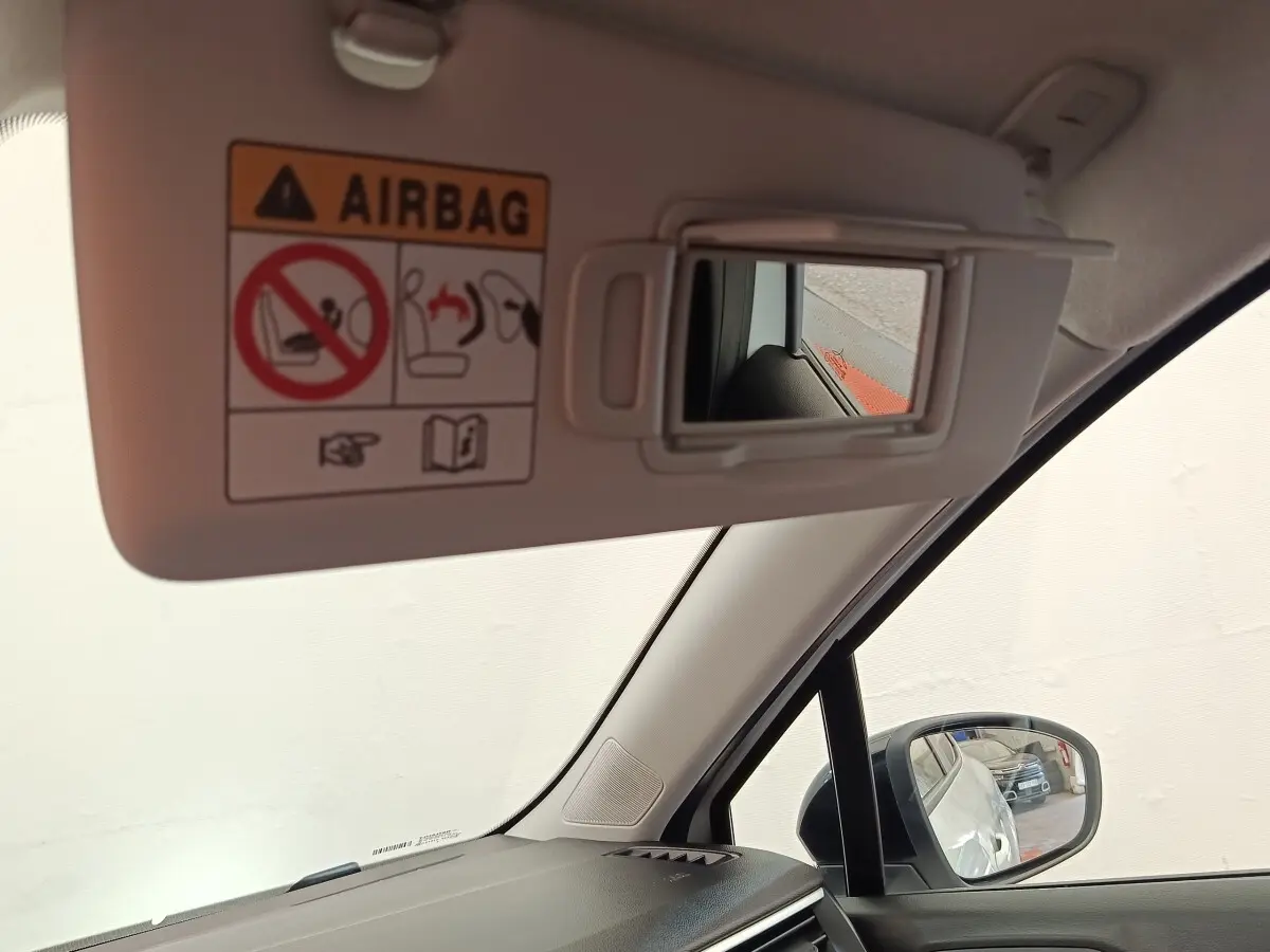 Vue intérieure côté conducteur du pare-soleil blanc avec miroir et rétroviseur extérieur noir de la Renault Clio 2023.