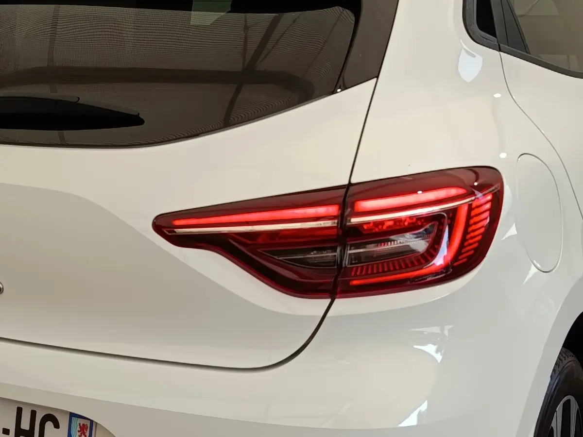 Gros plan sur le feu arrière droit rouge d’une Renault Clio blanche Evolution TCe 100 GPL, avec la trappe à carburant visible.