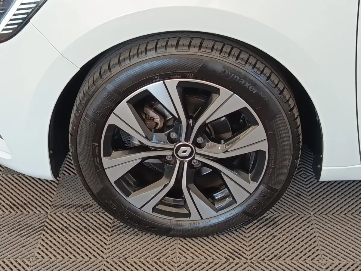 Gros plan sur la roue avant gauche d'une Renault Clio blanche avec jante alliage au design moderne.