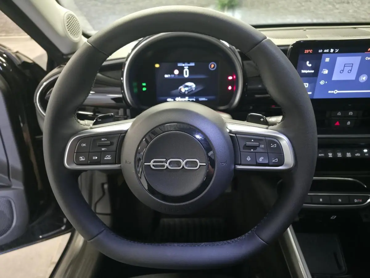 Vue rapprochée du volant noir marqué 600 du tableau de bord numérique et écran tactile du Fiat 600 Hybrid 2025.