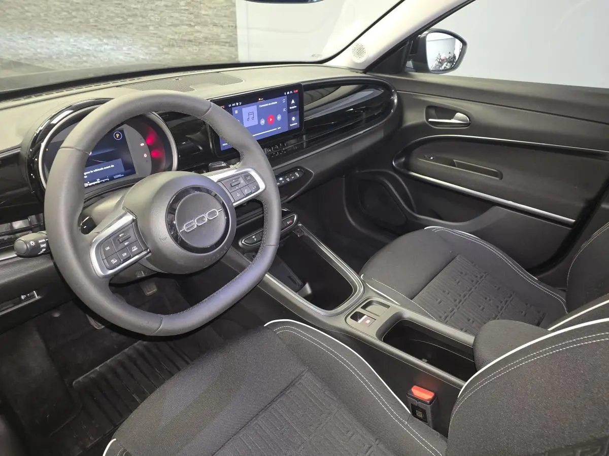 Vue intérieure côté conducteur de la Fiat 600 1.2 Hybrid noire, avec tableau de bord numérique et écran tactile central.