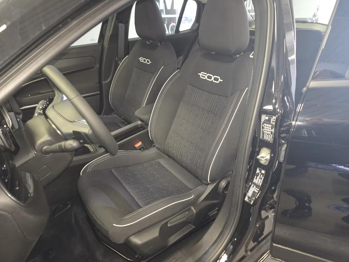 Vue intérieure côté conducteur de la FIAT 600 1.2 Hybrid noire, avec sièges spécifiques brodés et volant Soft-Touch.