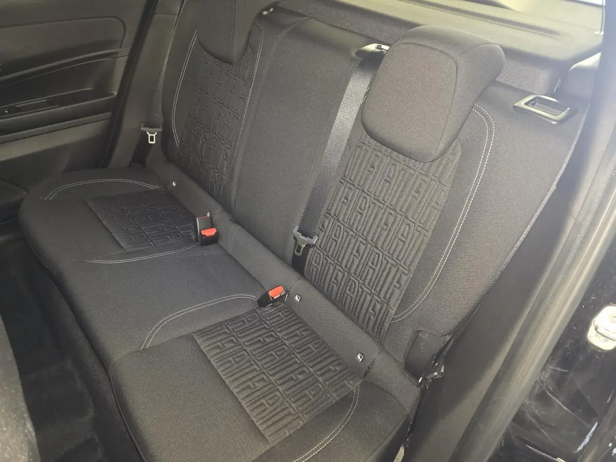 Vue intérieure de la banquette arrière noire du Fiat 600 Hybrid 2025 avec motifs FIAT embossés sur les dossiers.