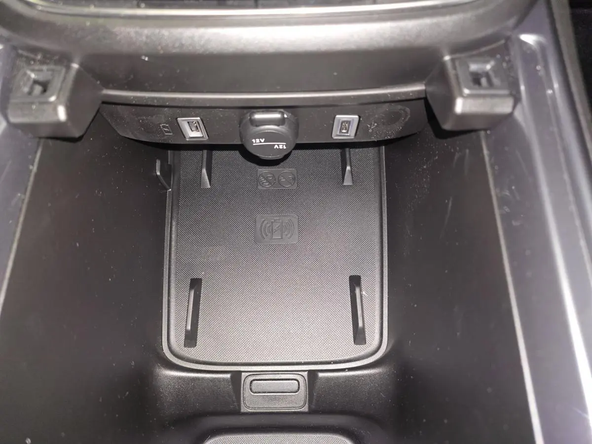 Gros plan sur la console centrale du Fiat 600 noir, montrant le chargeur smartphone par induction et deux ports USB.