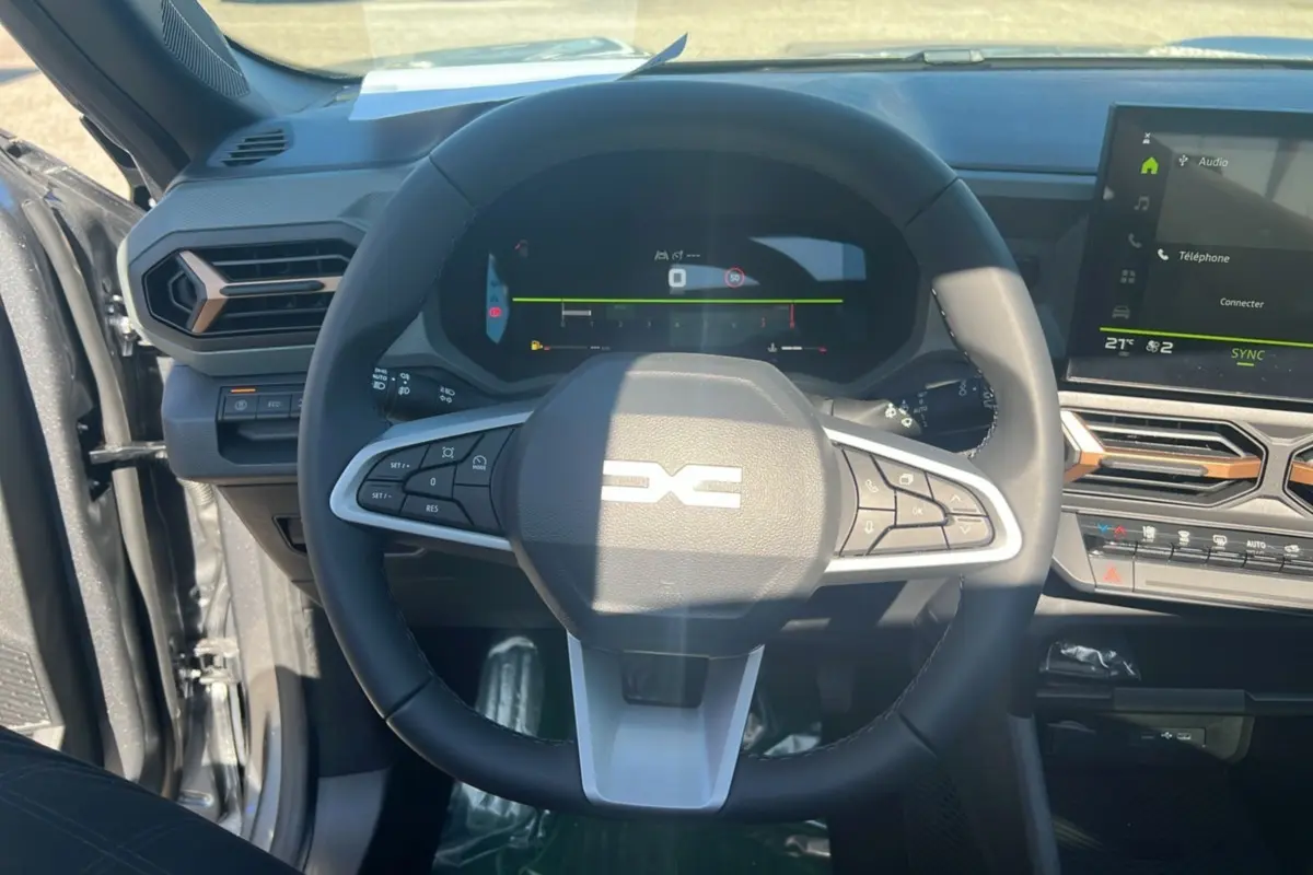 Vue intérieure centrée sur le volant du Dacia Bigster 2025 gris schiste, avec tableau de bord numérique et écran tactile.