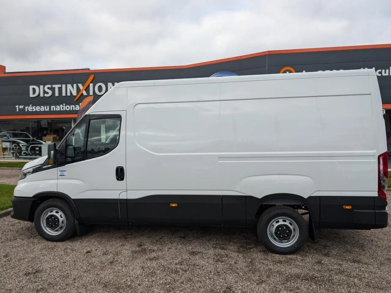 Profil côté gauche d'un utilitaire Iveco Daily blanc 2025 avec bas de caisse noir et bavettes sur roues.