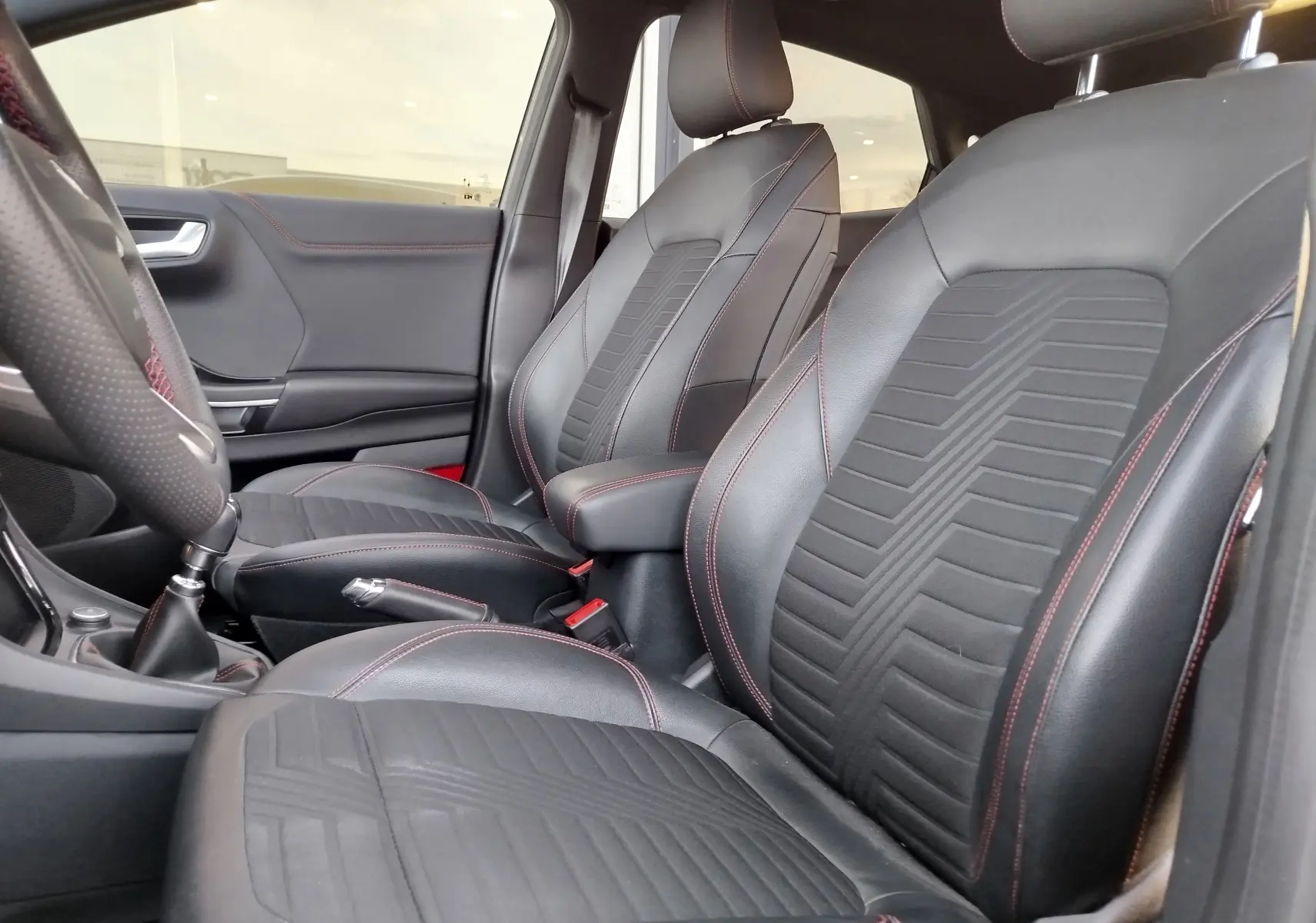 Vue intérieure des sièges avant noirs avec surpiqûres rouges du Ford Puma 1.0 EcoBoost 125ch mHEV ST-Line X de 2020.