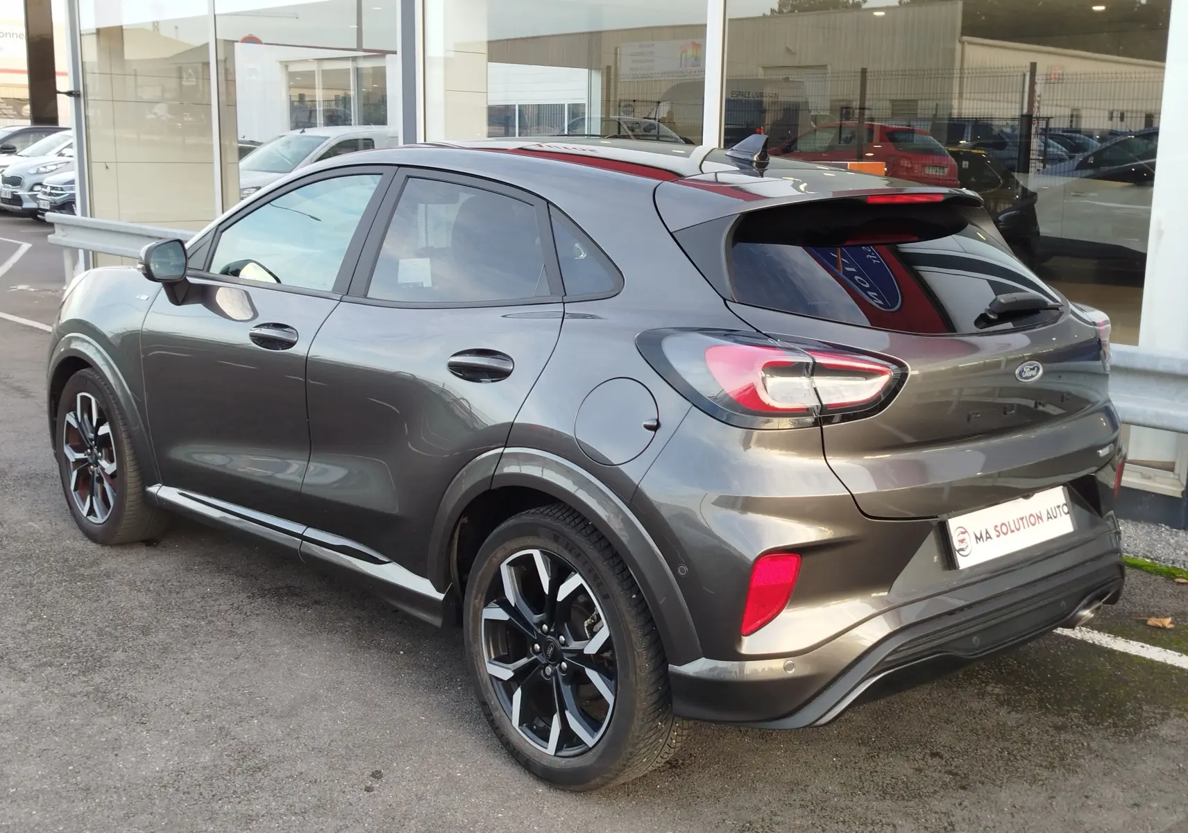 Vue 3/4 arrière droite d'une Ford Puma gris métallisé Fashion Gris Magnetic avec jantes alliage et vitres teintées.