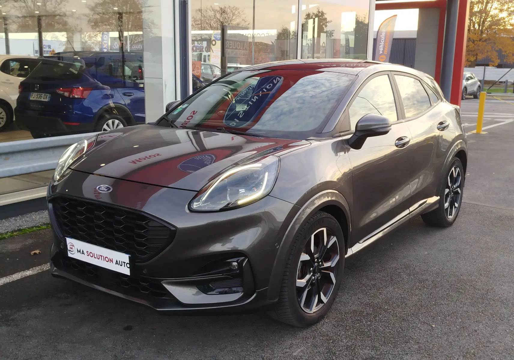 Ford Puma 1.0 EcoBoost 125ch mHEV ST-Line X gris métallisé en 3/4 avant droit, roues alliage et calandre noire.