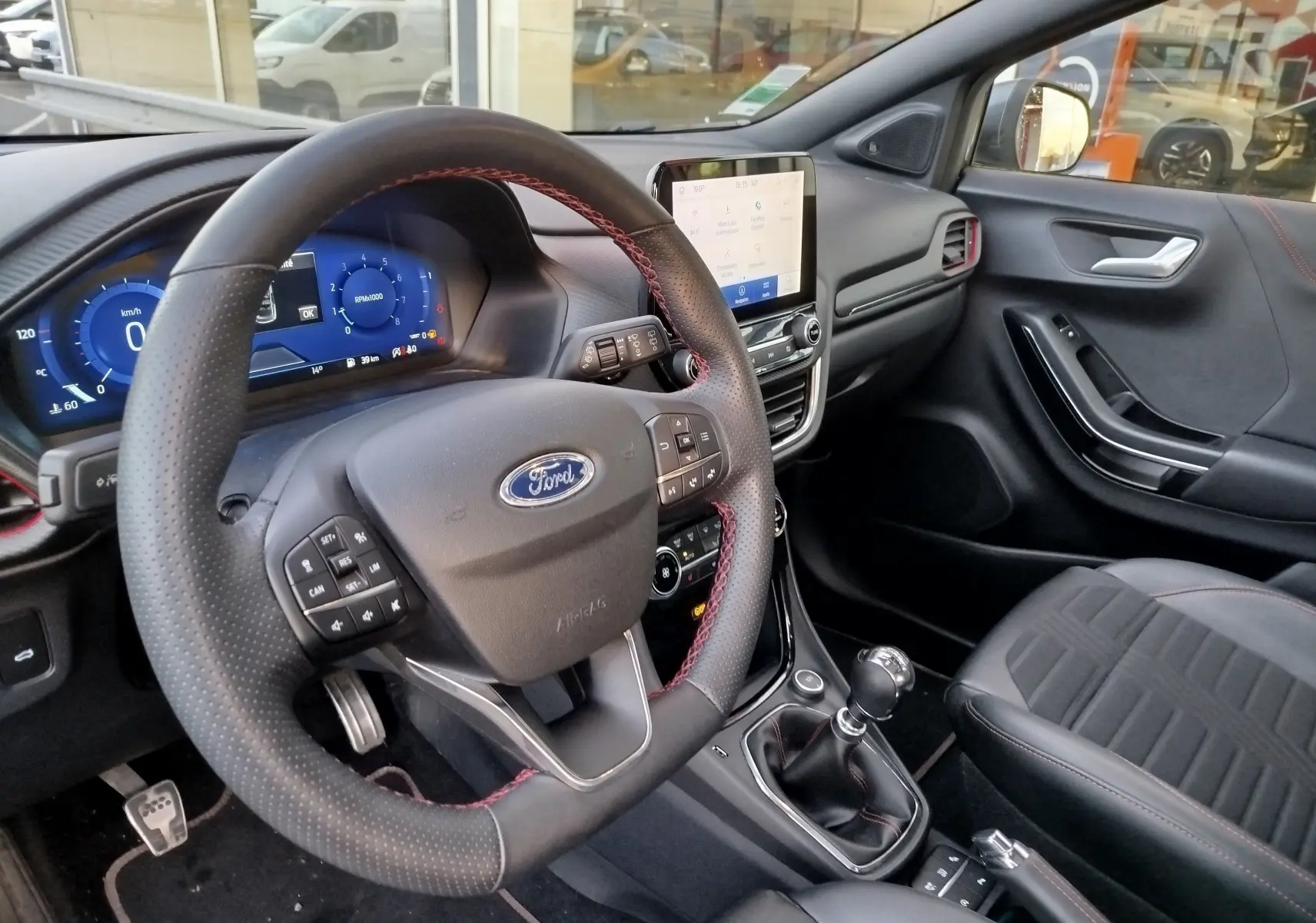 Vue intérieure côté conducteur du Ford Puma 1.0 EcoBoost 125ch mHEV ST-Line X avec volant cuir perforé et écran tactile central.