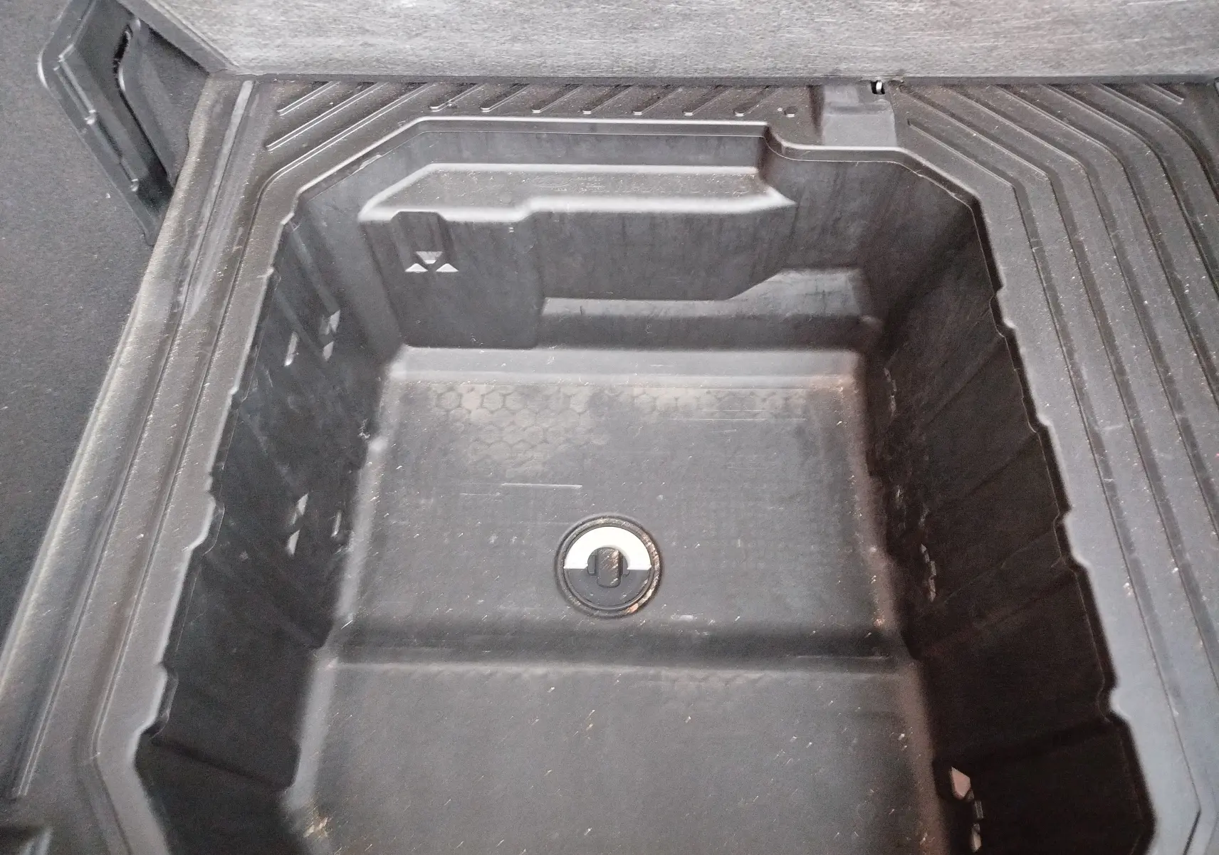 Coffre de rangement sous plancher en plastique noir dans un Ford Puma 2020 gris métallisé, vue plongeante.