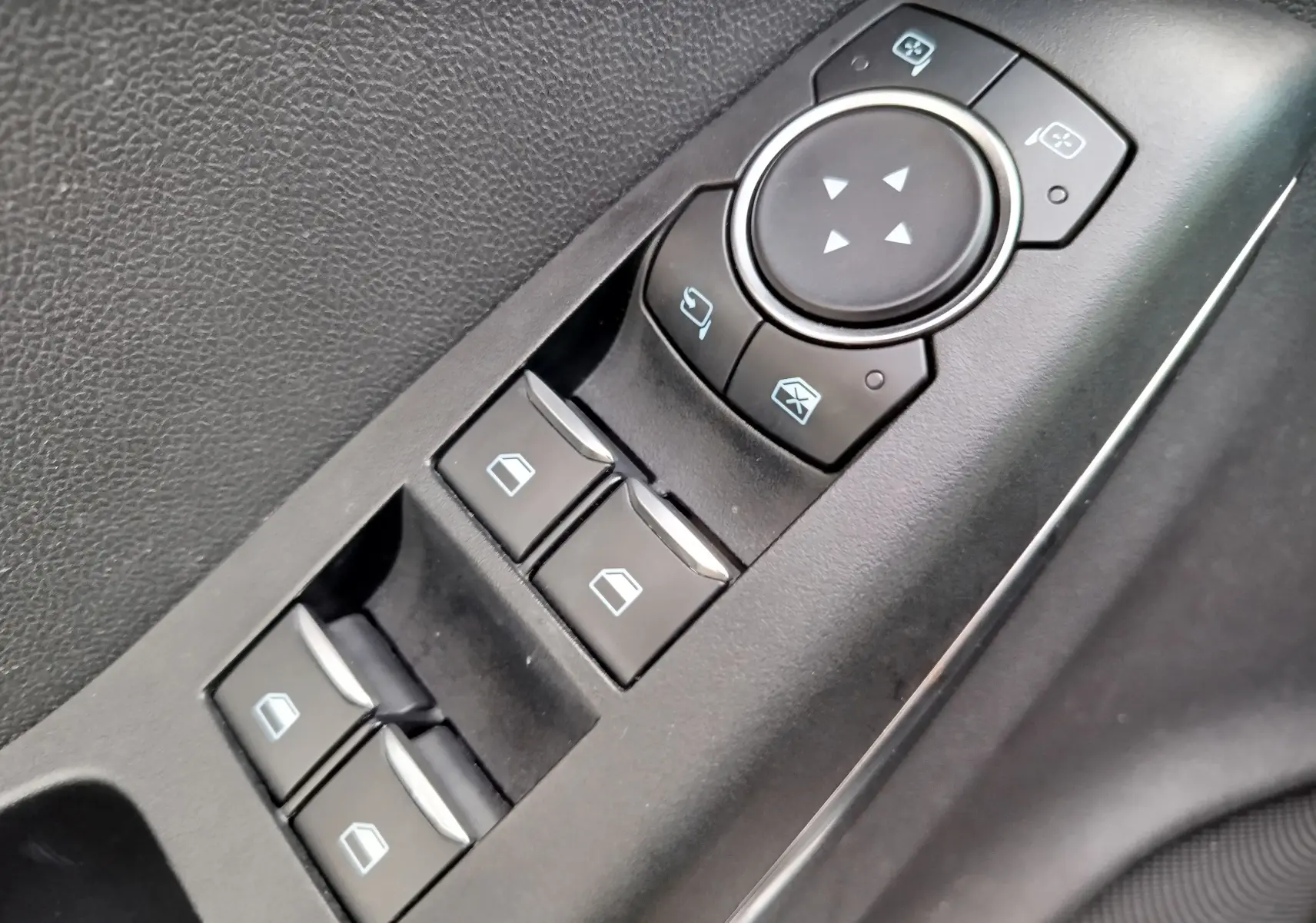 Gros plan sur les commandes de lève-vitres et réglage des rétroviseurs côté conducteur du Ford Puma gris Fashion Métallisé.