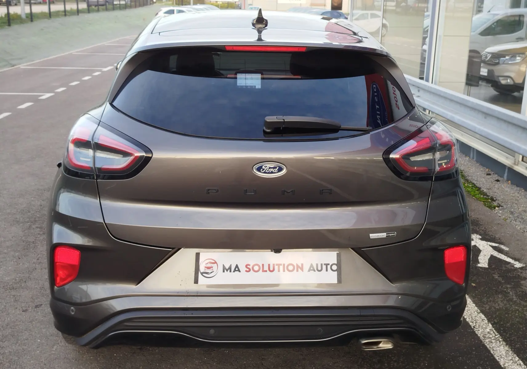 Vue arrière d'une Ford Puma gris métallisé avec feux LED et logo visible, stationnée devant un showroom.