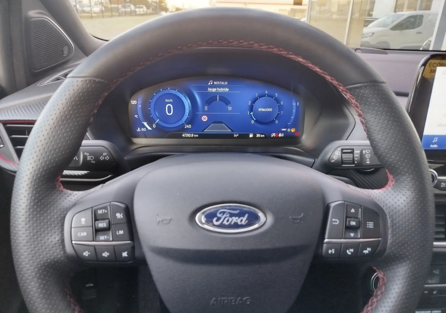 Vue intérieure centrée sur le volant perforé noir avec surpiqûres rouges du Ford Puma 1.0 EcoBoost gris métallisé de 2020.