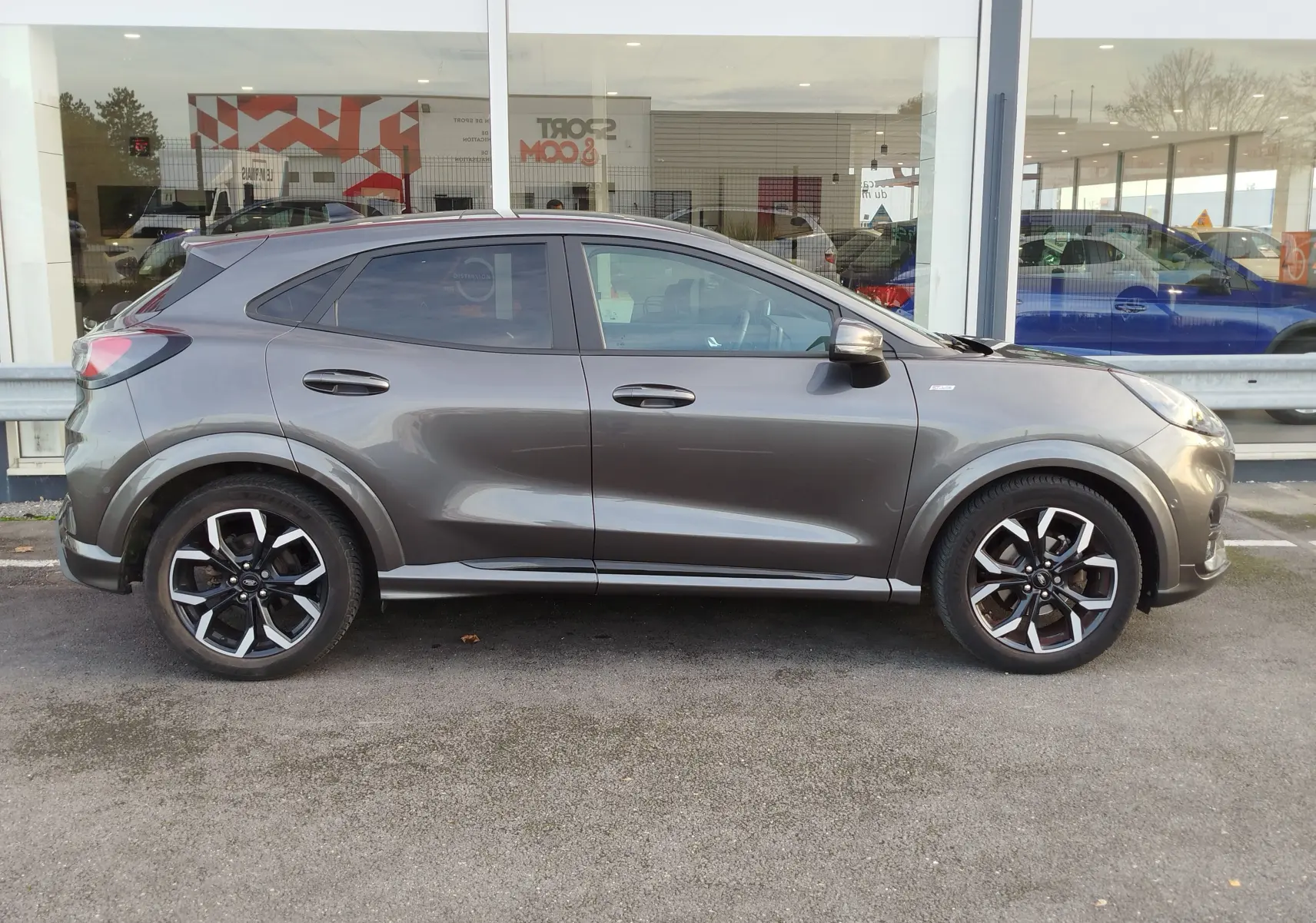 Profil côté gauche d'un Ford Puma gris métallisé Fashion, avec jantes alliage noires et détails sportifs ST-Line X.