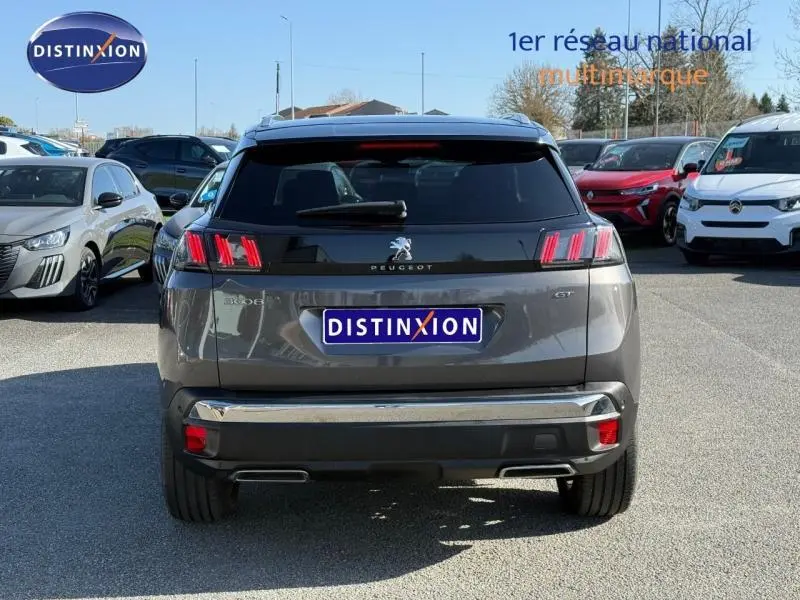 Vue arrière d'un Peugeot 3008 Gris Platinium 2024 avec feux arrière à trois griffes et logo central lumineux.